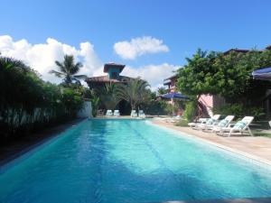 a swimming pool with chairs and a house at Ouro Sobre Azul Apart Hotel in Arraial d'Ajuda