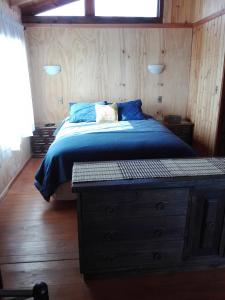 a bedroom with a bed with blue sheets and a dresser at Cabaña Amor in Isla de Maipo +28 photos