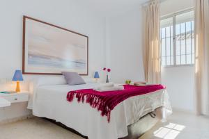 a white bedroom with a large bed with a red blanket at Duplex El Manantial in El Puerto de Santa María