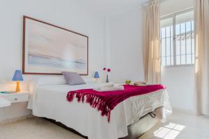 1 dormitorio blanco con 1 cama grande con manta roja en Duplex El Manantial, en El Puerto de Santa María