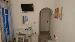 Habitación blanca con escritorio y TV en la pared. en Panorama Paros, en Parikia