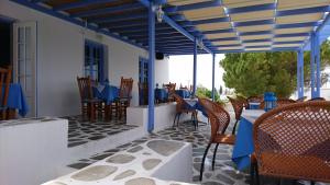 a patio with chairs and tables and a blue canopy at Panorama Paros in Parikia