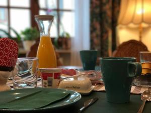 a table with green plates and cups and a bottle of orange juice at Pension Thilo in Bad Wildbad