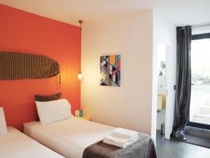 2 łóżka w pokoju z pomarańczowymi ścianami w obiekcie Bonvalot Guest House w mieście Paço de Arcos