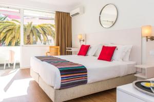 a bedroom with a large white bed with red pillows at Hotel Londres Estoril / Cascais in Estoril