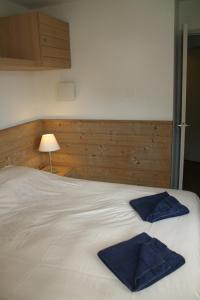 Una cama blanca con dos toallas azules. en Le Britania 507 en La Tania