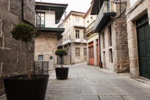 eine leere Gasse mit zwei Topfbäumen auf dem Bürgersteig in der Unterkunft Loft Medieval in Ribadavia