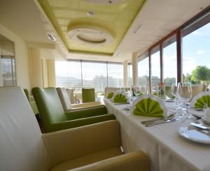 a dining room with a long table with green chairs at Hotel-Restaurant Gruber in Pöllau