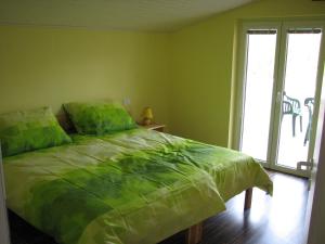 a bedroom with a bed with a green comforter at Apartma Furlan in Štanjel