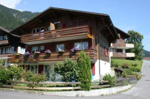 ein großes Holzhaus mit Blumen auf dem Balkon in der Unterkunft Chalet Silky in Adelboden