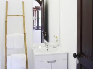 Foral Guest House - Óbidos في أوبيدوس: حمام أبيض مع حوض ومرآة