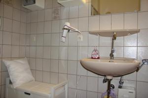 a bathroom with a sink and a chair at Kleine Seenadel in Dornumersiel