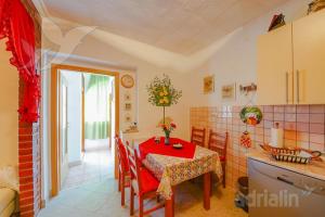 a kitchen and dining room with a red table and chairs at Apartments Ivka & Garden in Senj