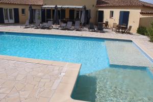 a swimming pool with chairs and a house at Villa des Cammaous in Vacquières