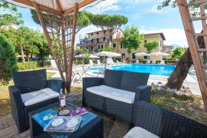 un patio con 2 sillas, una mesa y una piscina en Hotel Apuana, en Marina di Pietrasanta
