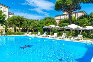 a large swimming pool with chairs and umbrellas at Hotel Apuana in Marina di Pietrasanta