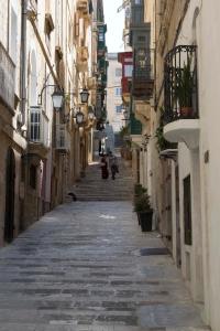 an empty alley with some people walking down it at Vincenti Strait Street Suite in Valletta