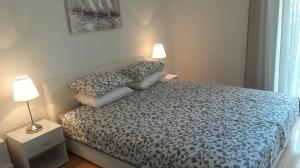 a bedroom with a bed with two pillows and two lamps at Apartmani Vitturi in Kaštela