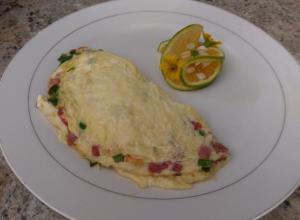 a white plate with an omelet and a slice of lime at Polish Princess Guest House in Port Antonio