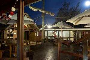a deck with tables and umbrellas at night at Bay Cove Inn in Jeffreys Bay