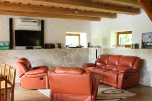 a living room with leather furniture and a flat screen tv at Tammeveski Holiday House in Kobruvere