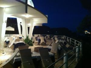a group of chairs and tables on a balcony at night at Hotel Eden in San Domino