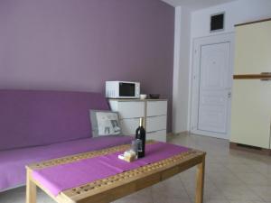 a purple couch with a bottle of wine on a table at Apartment Stiller in Novalja