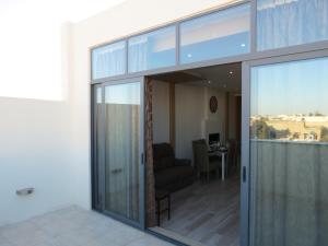 a living room with sliding glass doors and a chair at The Ivies in Mosta
