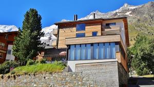 uma casa nas montanhas com uma parede de pedra em Elite Alpine Lodge - Apart & Breakfast em Saas-Fee