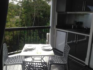a table and chairs on a balcony with a kitchen at Studio Bas du Fort Guadeloupe in Le Gosier