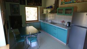 a kitchen with blue cabinets and a table and a refrigerator at Apartamentai Galerija in Palanga