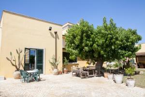 un patio con un árbol, una mesa y sillas en B&B I Tre Ulivi, en Salice Salentino