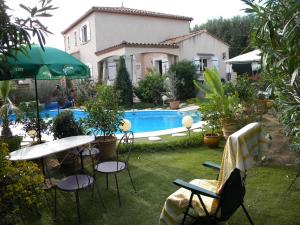 a patio with a table and chairs and a pool at Chez Patrick Roujan in Roujan