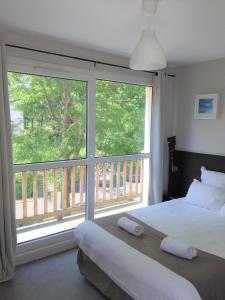 Sweet Home Appart'Hôtel Deauville Sud في دوفيل: غرفة نوم بسرير ونافذة كبيرة