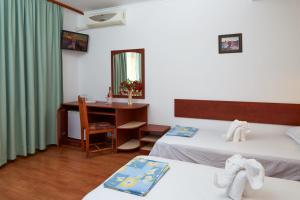 een kamer met 2 bedden en een bureau met een spiegel bij Hotel Sunrise in Ravda