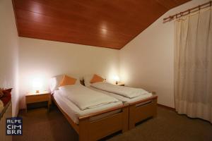 フォルガリーアにあるChalet Lailaのベッドルーム1室(ベッド1台、ランプ2つ、テーブル2台付)