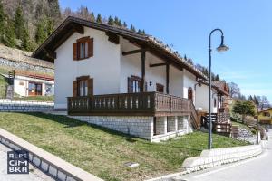 uma pequena casa branca com uma varanda numa rua em Chalet Laila em Folgaria