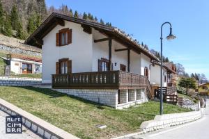 a small white house with a balcony on a street at Chalet Laila in Folgaria