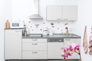 a white kitchen with white cabinets and a microwave at City Pension in Plettenberg