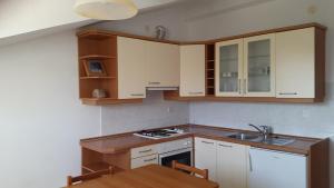 a kitchen with white cabinets and a wooden table at Apartments Ukić in Tribunj