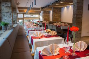 a row of tables in a restaurant with red and white table settings at Hotel & Relax Zone Cattleya in Krushuna