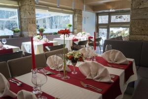 a dining room with tables with red and white table settings at Hotel & Relax Zone Cattleya in Krushuna