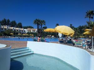 a swimming pool with people sitting in chairs and umbrellas at Cabana da Ria in Cabanas de Tavira