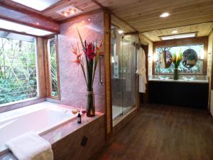 a bathroom with a bath tub with a vase of flowers at Lotus Garden Cottages in Volcano