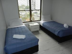 two beds in a small room with a window at Kalua Holiday Apartments in Maroochydore