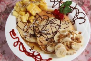 a plate of pancakes with syrup and bananas and fruit at Lands in Love Hotel and Resort in Colonia Palmareña