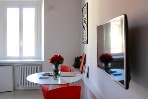ミラノにあるDesign apartment Porta Veneziaの白いテーブルと赤い椅子、花瓶