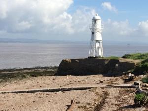 a lighthouse sitting on top of a cliff next to the ocean at The Nook @ Drop Anchor in Portishead