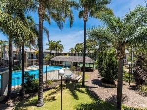 um resort com piscina e palmeiras em Mandurah Motel and Apartments em Mandurah