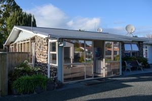 a building with glass doors and a fence at Kauri Lodge Motel in Kaitaia